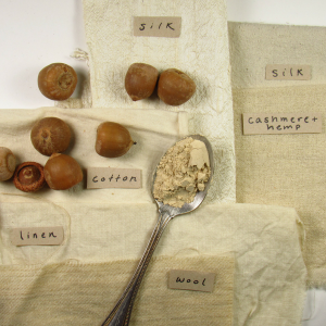 acorns and a spoon of tan powder on pale fabrics
