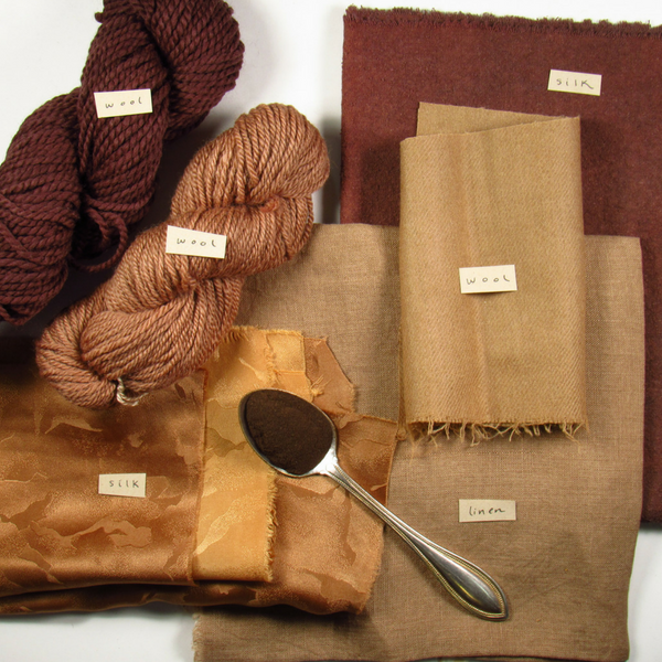 a spoon of brown powder on a stack of tan and brown fabrics and yarns