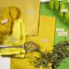 A spoon of yellow powder on a stack of bright yellow and green fabrics and yarn