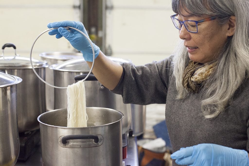 Kathy Hattori holding a skein of yarn over a pot