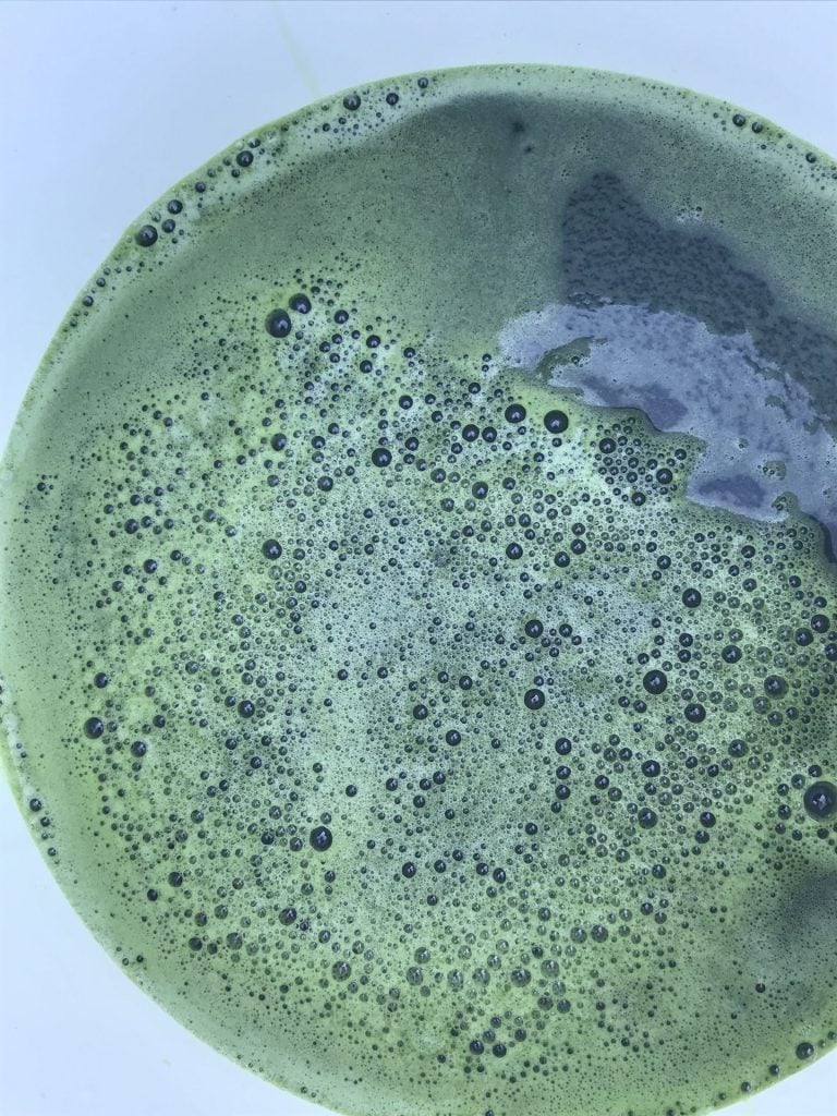 blue liquid with green green foam in a white bucket