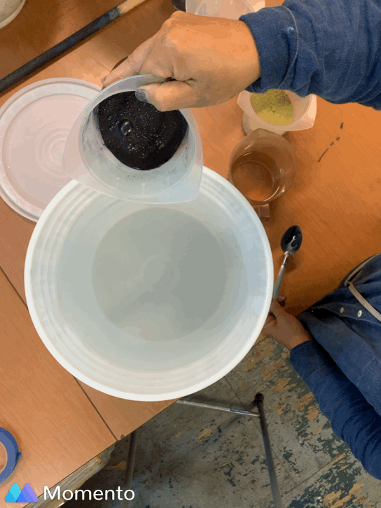 Pouring indigo dissolved in water into a larger white bucket with water