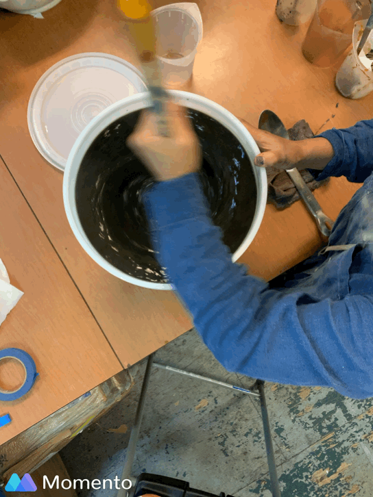 Overhead shot of stirring an indigo vat with a large wooden dowel