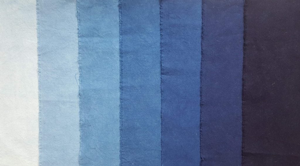 Seven swatches of blue fabric from very pale on the left to dark navy blue on the right