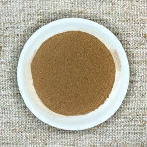 tan powder on a white bowl sitting on a woven fabric background