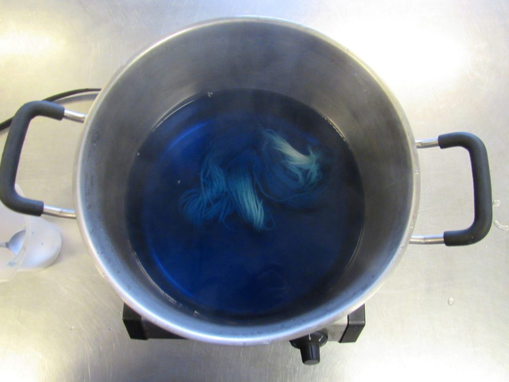 skein of yarn in bright blue dyebath