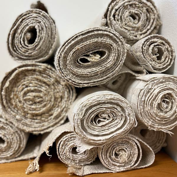 Rolls of different fabrics piled up on a wooden table