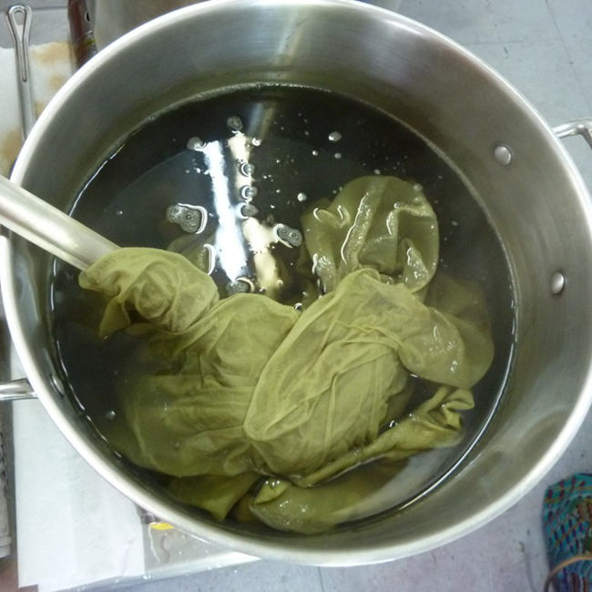 yellow-green fabric in a stainless steel dyepot