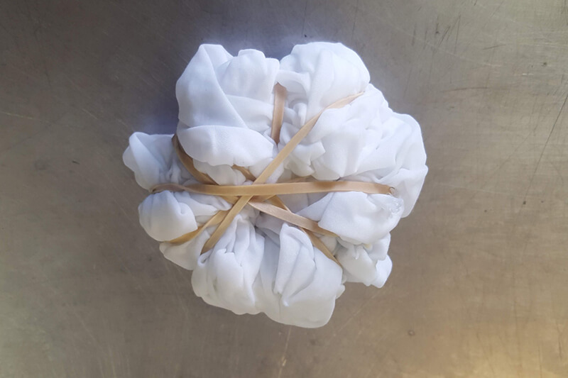 a bundle of white fabric wrapped tightly with multiple rubber bands