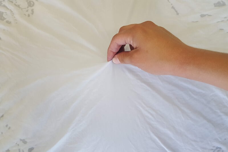 hand pinching the center of white fabric