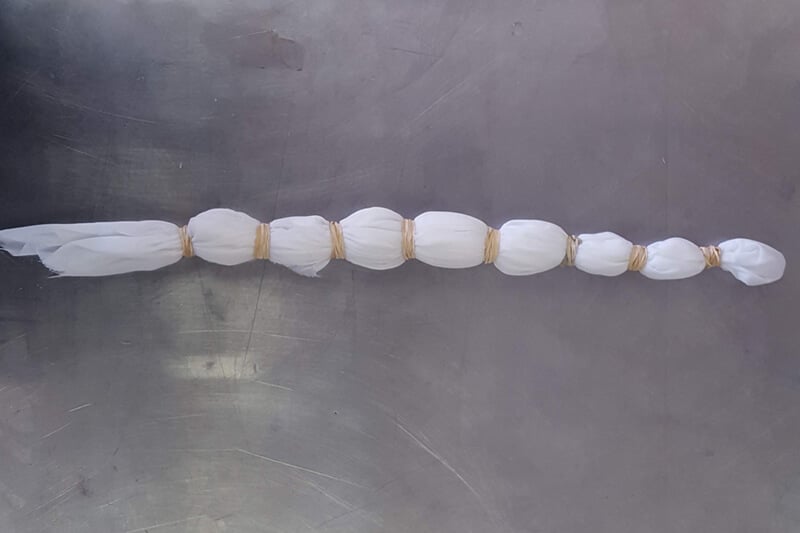 white fabric tied with multiple rubber bands on a silver table