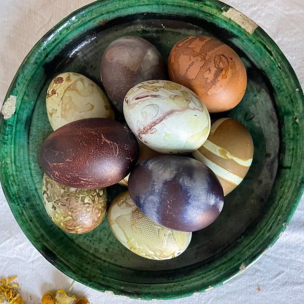 multicolored dyed eggs in a green ceramic bowl