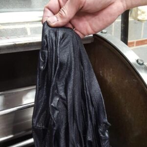 A hand holding damp fabric that has been dyed black