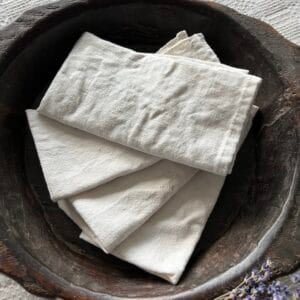 4 white hemp-cotton napkins folded in a dark wood bowl